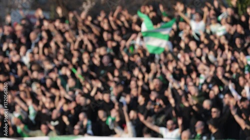 Many fans supporting soccer team at stadium. Blurred crowd of people at football stadium.