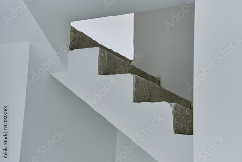 Unfinished concrete staircase in modern minimalist interior. New apartment with raw construction elements and white walls. Building under repair