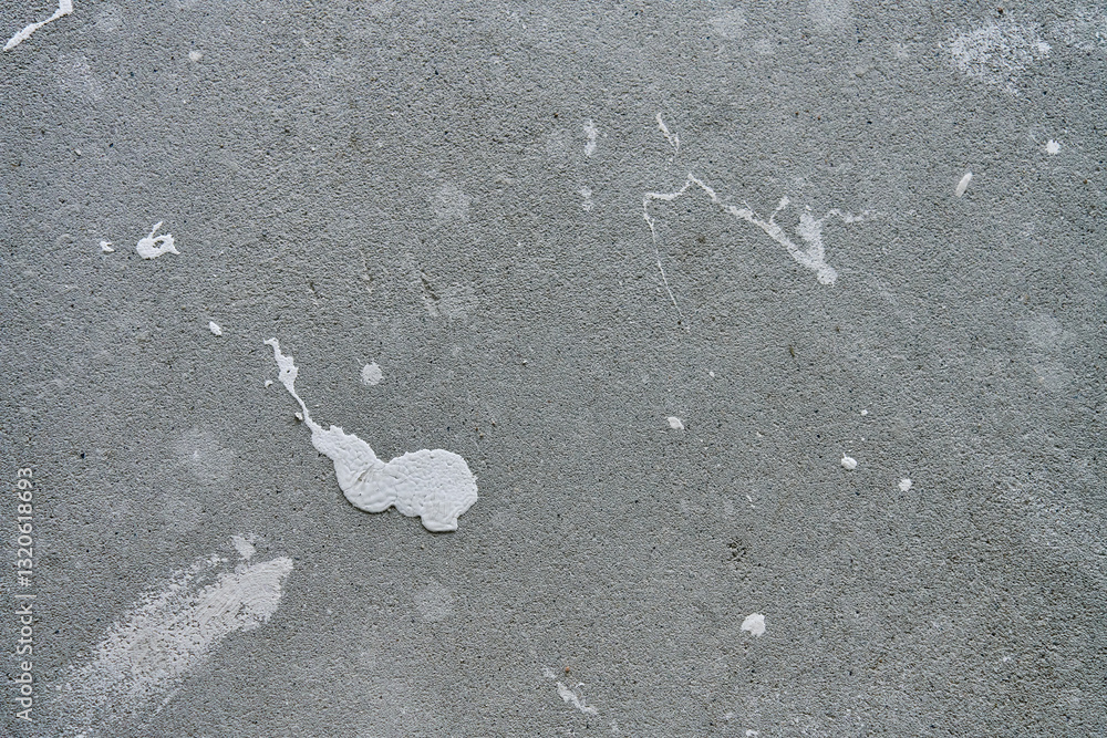 Close-up of concrete wall with white paint splashes and rough texture. Background for construction and renovation concep