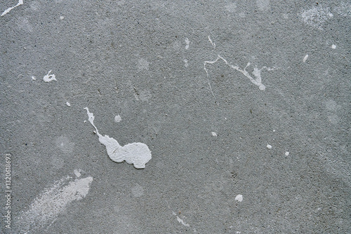 Close-up of concrete wall with white paint splashes and rough texture. Background for construction and renovation concep