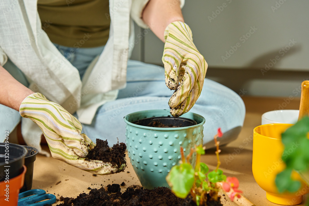 Woman sits on the floor, repotting plant using gardening tools and fresh soil. Concept of home gardening, plant care and eco-friendly lifestyle