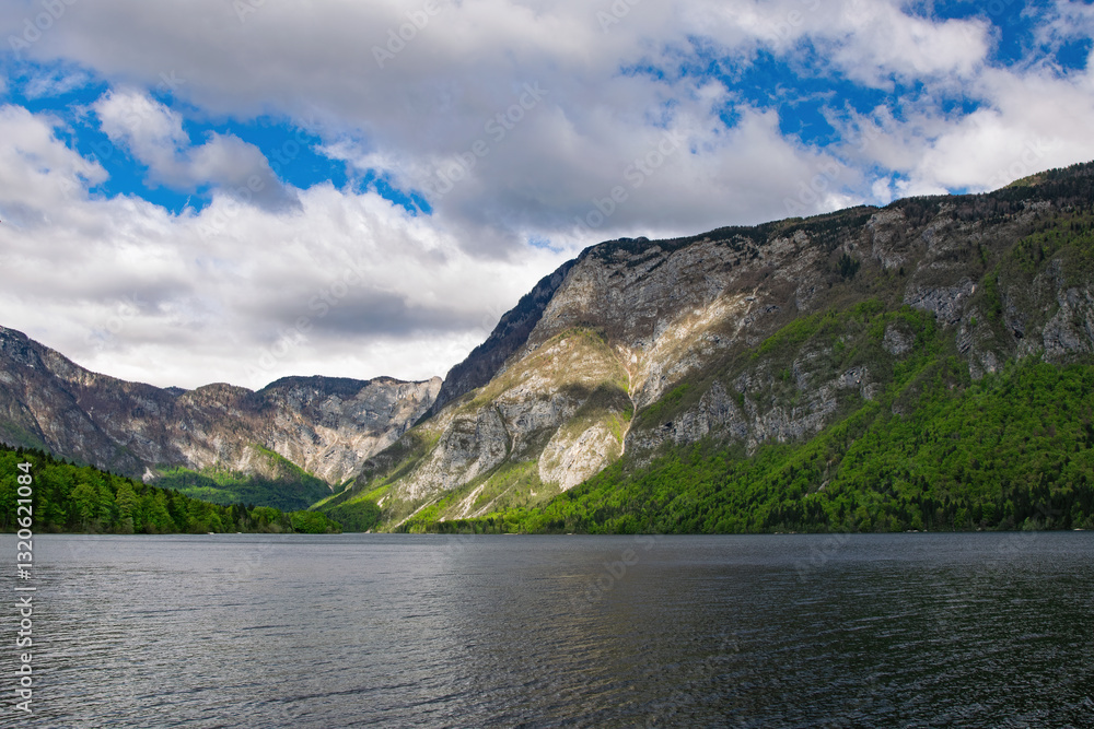 Scenic view of Lake Bohinj with mountains and cloudy sky in the background, showcasing the beautiful nature of Slovenia Scenic view of Lake Bohinj with mountains and cloudy sky in the background, showcasing the beautiful nature of Slovenia