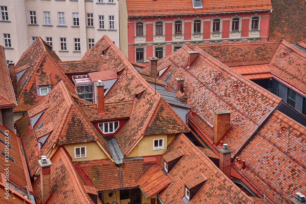 Scenic aerial view of historic European rooftops covered with red clay tiles and chimneys. Old town architecture and traditional cityscapes in European city. Panoramic view of Graz, Austria