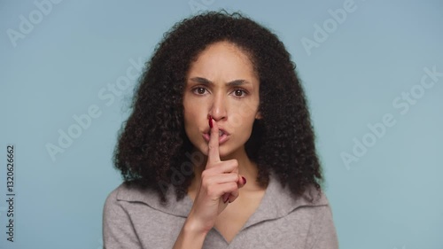 Serious woman making shushing gesture for silence