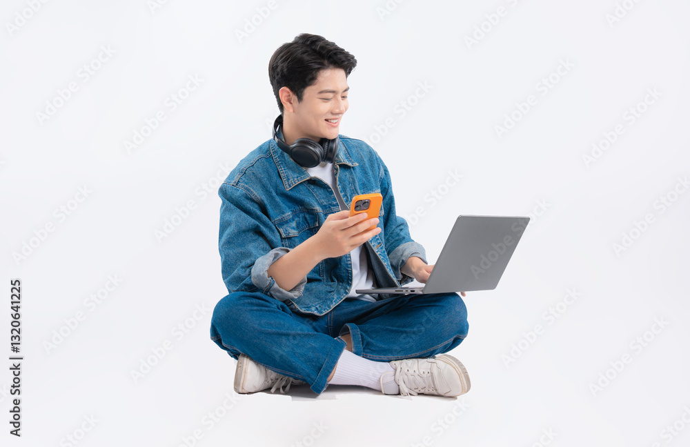 Full body image of Asian guy using laptop and phone and headphone on white background Full body image of Asian guy using laptop and phone and headphone on white background