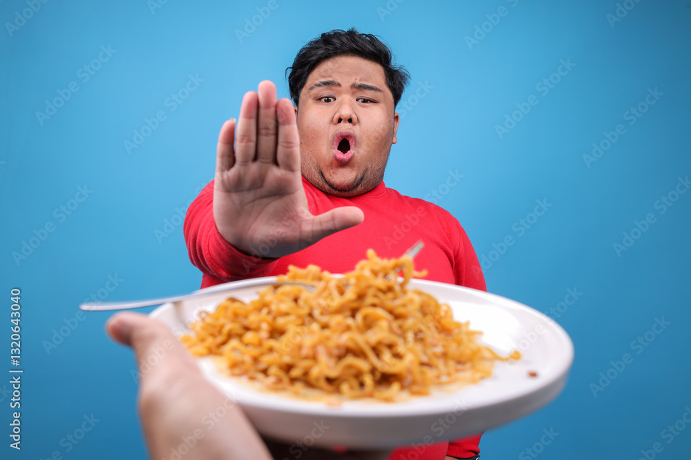 Young Asian Fat Man Rejecting Fried Noodles Isolated on Blue Background Young Asian Fat Man Rejecting Fried Noodles Isolated on Blue Background
