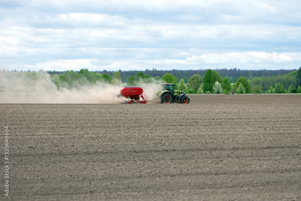 Obraz premium tractor in a field, planting crops on an agricultural field. tractor working in the field, harvesting, business, agriculture. soil preparation, spring season. Seasonal work. Farmland. Diesel. Ukraine