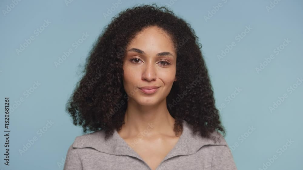 Playful woman winking with a confident smile on blue background Playful woman winking with a confident smile on blue background
