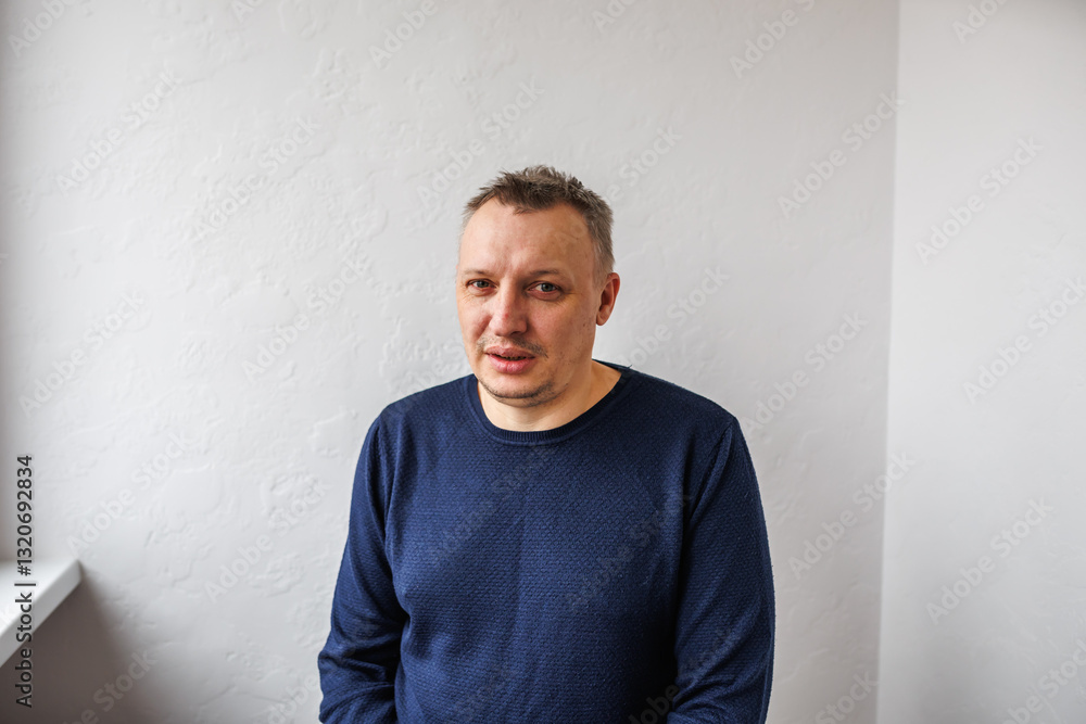 Portrait of a cheerful middle-aged man wearing a gray hoodie, standing against a textured stone wall in natural light. Portrait of a cheerful middle-aged man wearing a gray hoodie, standing against a textured stone wall in natural light.