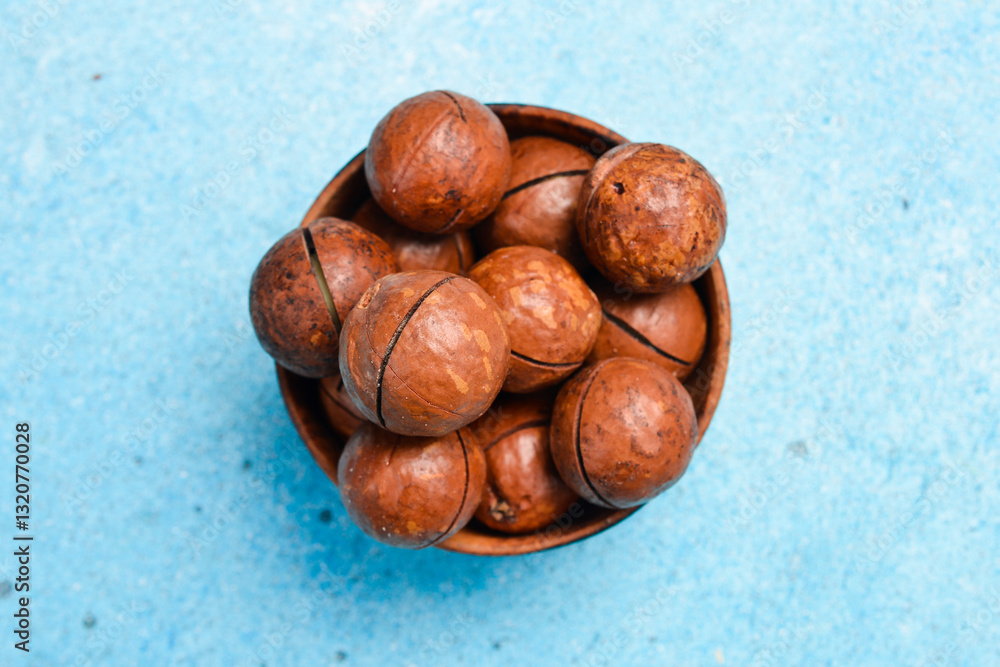Obraz premium Roasted delicious macadamia nuts on a blue stone background. Top view.