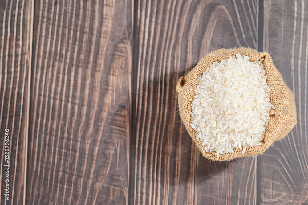 Raw White Rice in Burlap Sack on Rustic Wooden Table