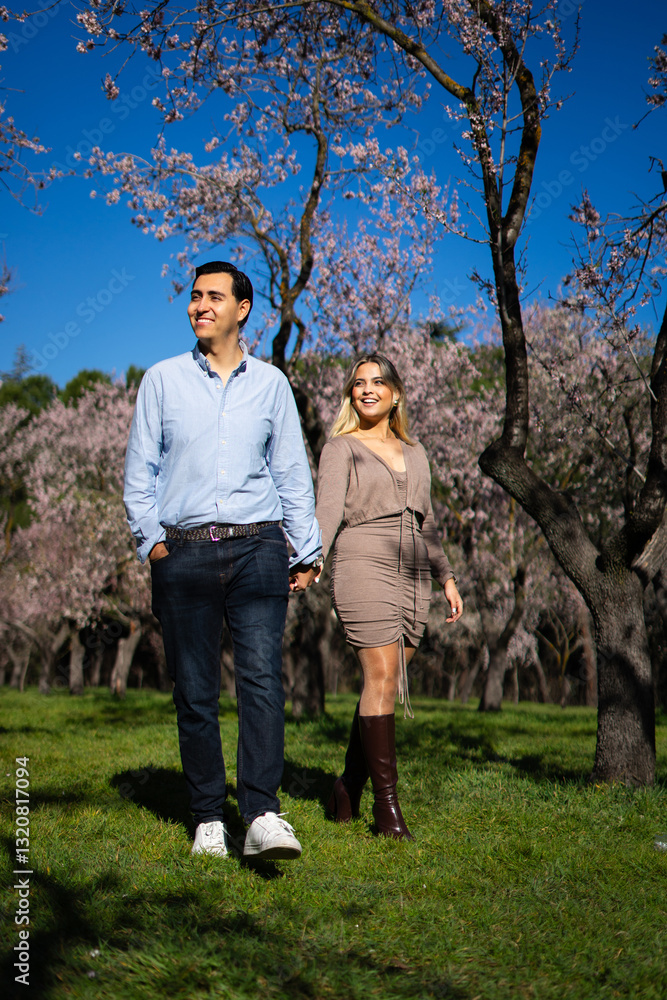 Happy couple walking through almond orchard in bloom