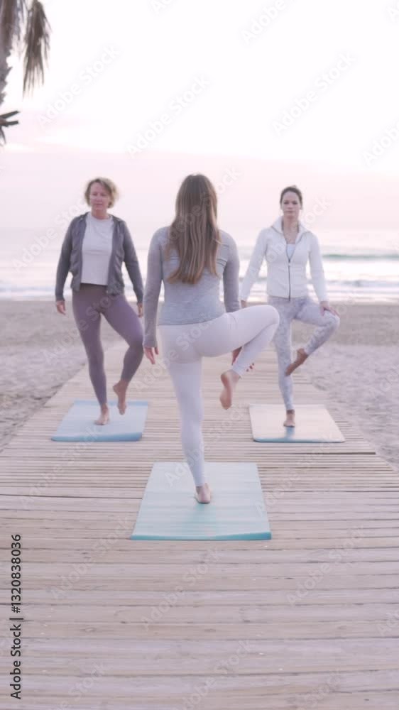 A yoga teacher conducts a workout on the beach for women. The concept of yoga practice and stretching by the sea. A yoga teacher conducts a workout on the beach for women. The concept of yoga practice and stretching by the sea.