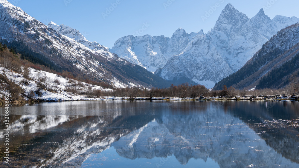 Fototapeta premium Dombay, Karachay-Cherkessia. Teberda National Park. Lake Tumanly-Gel or Tumanly-Kol (Misty Lake) is in valley of Gonachkhir River. Snowy peaks of Mount Chotcha are reflected in lake as in mirror.