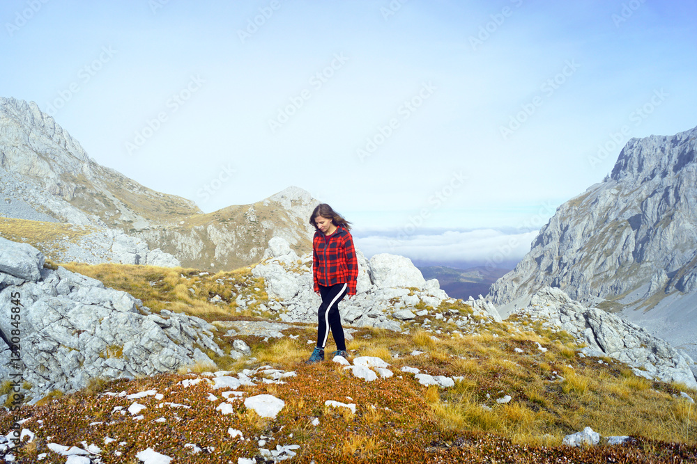 Obraz premium Shot List travel: woman walking in beautiful mountainous area on sunny autumn day (Komovi Nature Park, Montenegro). Solo nature travel: female hiker high in the mountains. Exploring the Balkans.