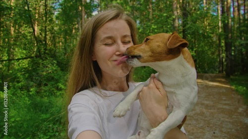 A joyful woman enjoying her time with a playful dog in a lush and vibrant green forest