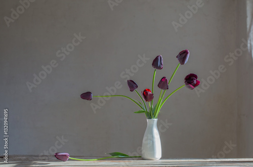 tulips in white vase on background old wall