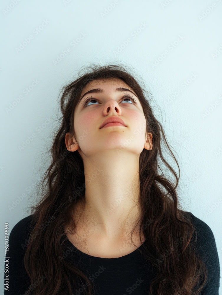 Young woman with dark hair and light skin looking upwards towards ceiling, showing slight smile on face.