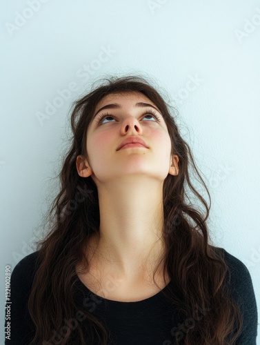 Obraz na płótnie Young woman with dark hair and light skin looking upwards towards ceiling, showing slight smile on face. w salonie