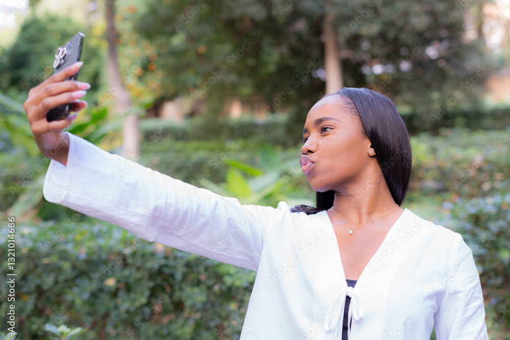 Young african american businesswoman taking a selfie with her smartphone in a park, making a duckface and holding the phone with her right hand Young african american businesswoman taking a selfie with her smartphone in a park, making a duckface and holding the phone with her right hand