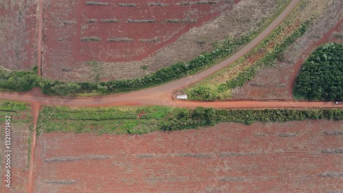 Top down view of a road with three directions, turn-off on red fields with green bushes, above, zoom out, copy space
