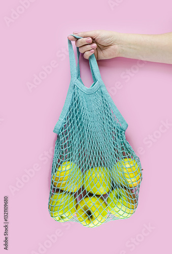 Eco-friendly Mesh Bag with Fresh Apples on Pink Background. photo