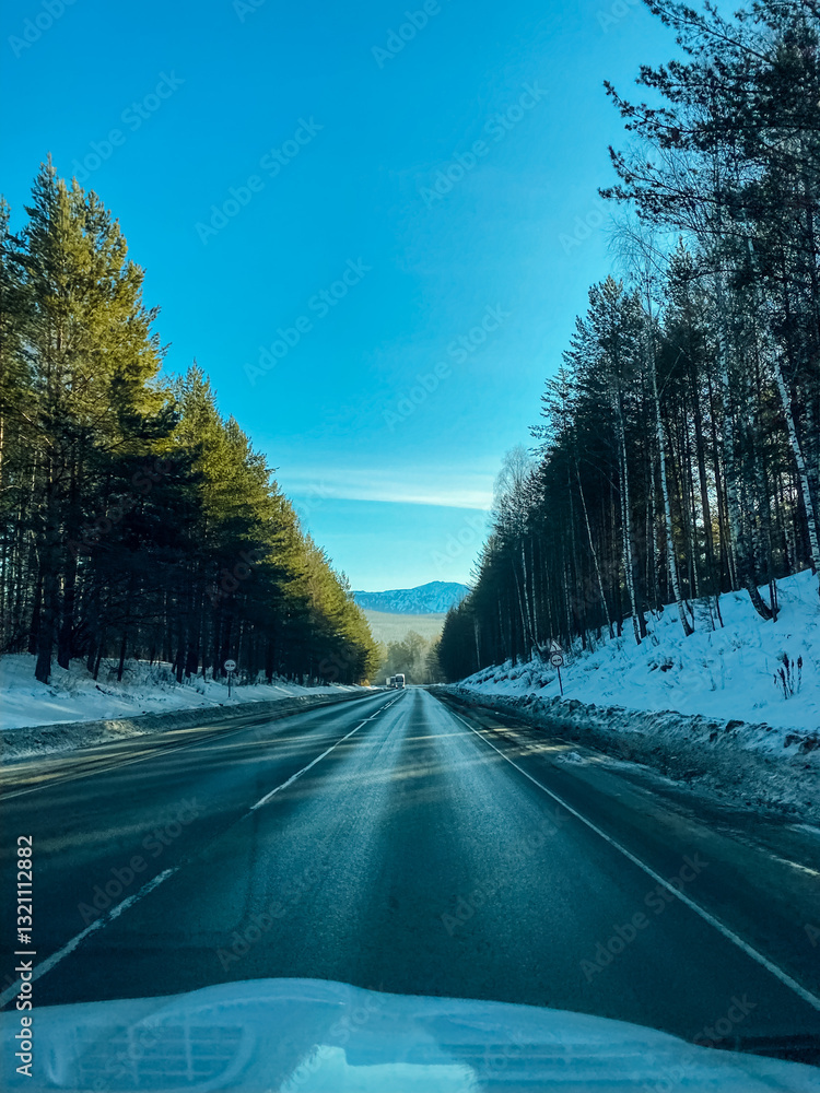 A car is making its way carefully down a snowy road, surrounded by trees on both sides creating a picturesque winter landscape, ensuring a safe journey through this frosty scene A car is making its way carefully down a snowy road, surrounded by trees on both sides creating a picturesque winter landscape, ensuring a safe journey through this frosty scene