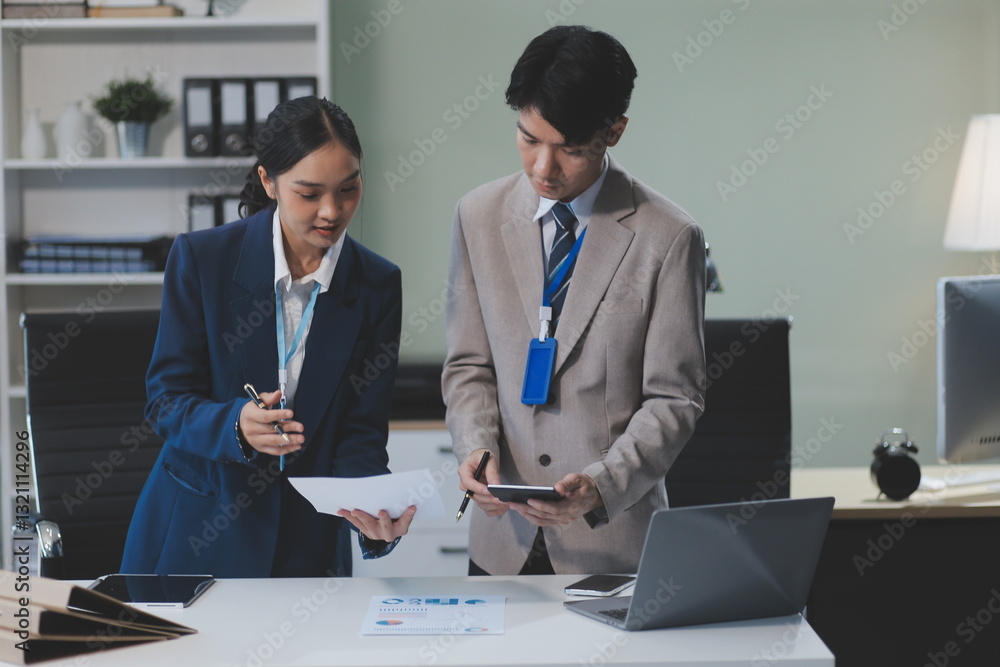 Cheerful businesspeople using a laptop in an office. Happy young entrepreneurs smiling while working together in a modern workspace. Two young businesspeople sitting together at a table. Cheerful businesspeople using a laptop in an office. Happy young entrepreneurs smiling while working together in a modern workspace. Two young businesspeople sitting together at a table.