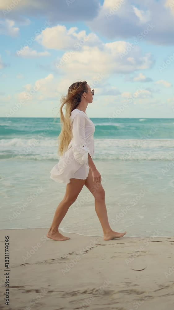 Happy woman on oceanic shore, side view of slender female vacationer walking on coast. Breathtaking seascape in horizon, slow motion vertical video, traveling and tourism in summer vacation, good mood Happy woman on oceanic shore, side view of slender female vacationer walking on coast. Breathtaking seascape in horizon, slow motion vertical video, traveling and tourism in summer vacation, good mood