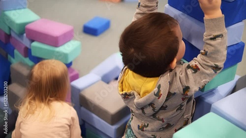 Playful toddlers stack colorful foam blocks, building tall towers in bright playroom. Playful toddlers develop motor skills and creativity through engaging play toddlers enjoy hands-on learning 