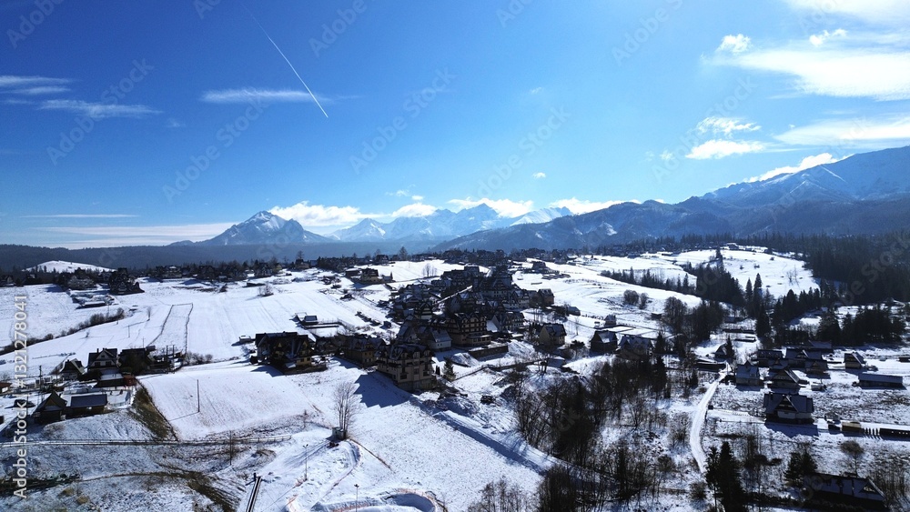 Murzasichle, Tatra Mountains, Poland. View of a mountain village near Zakopane during winter. In the background are the high Tatra Mountains, the peaks of which are covered with snow.
