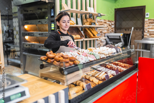 Fotografija Baker arranging pastries in display case at bakery shop