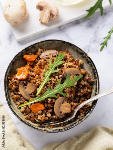 Photos Top view of buckwheat porridge dish with mushrooms, carrots and lettuce, healthy