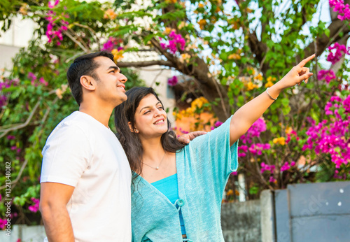 Young Indian couple sharing a joyful morning nature walk, smiling, pointing, and bonding together