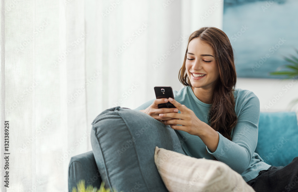 Beautiful young woman relaxing at home and using her smartphone Beautiful young woman relaxing at home and using her smartphone