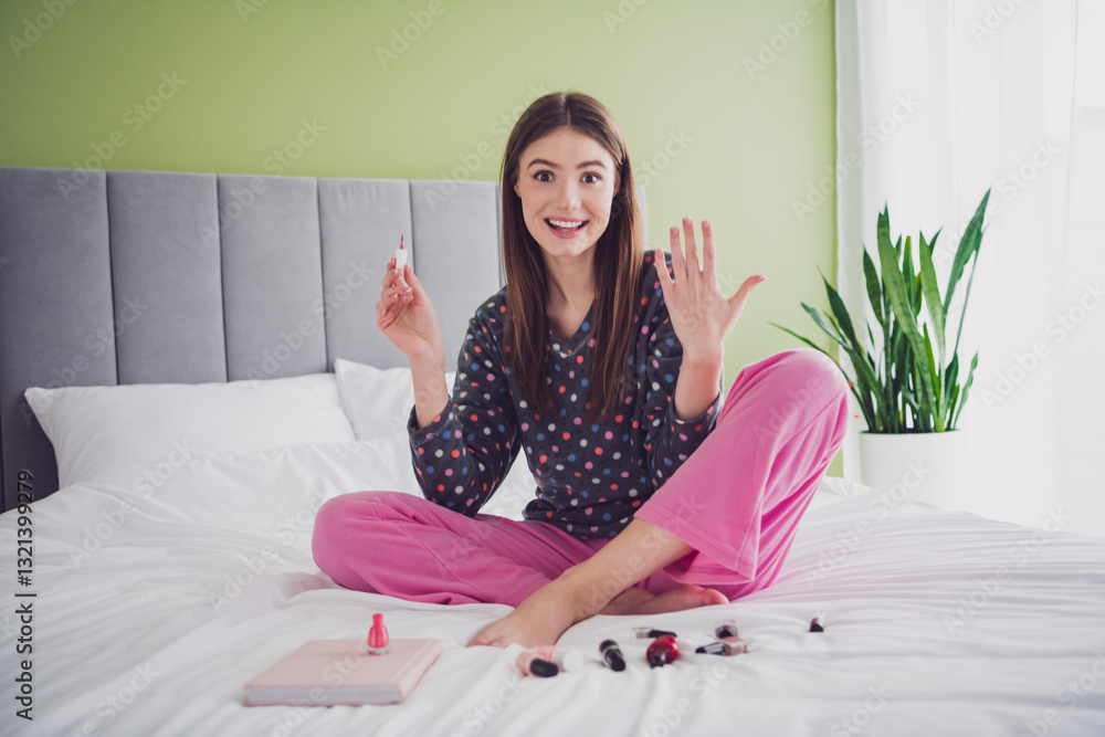 Young woman painting nails in a modern bedroom, enjoying leisure time and showcasing a captivating smile in cozy sleepwear Young woman painting nails in a modern bedroom, enjoying leisure time and showcasing a captivating smile in cozy sleepwear