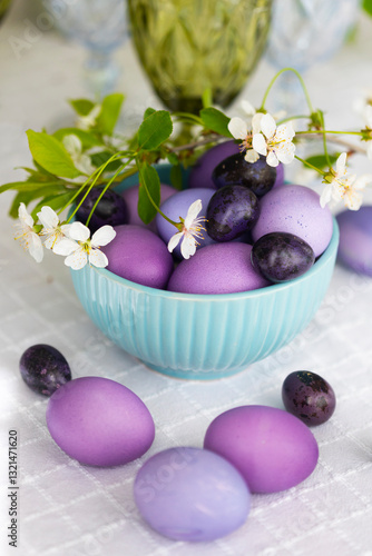Easter eggs in shades of lilac and purple with green blooming branch in festive or holiday table