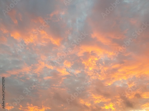 Morning Sunrise - Orange Clouds; Grey Clouds colored orange and yellow by the rising sun, against a pale blue sky.