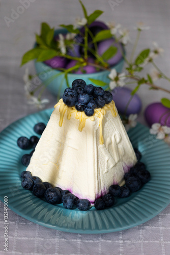 Holiday laid table for Easter with Russian traditional dish called Easter made of cottage cheese, painted eggs in shades of lilac and purple with green blooming branch
