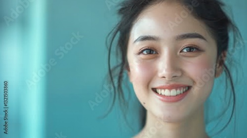 Young woman smiling against a light blue background in a bright and cheerful atmosphere during the day