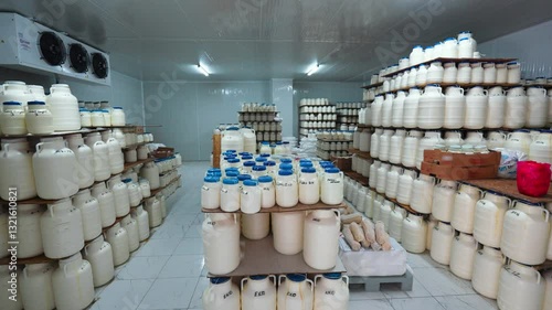 A dairy industry worker handling cheese storage containers in a refrigerated facility,ensuring food safety and quality preservation.This controlled environment helps maintain hygiene aging of cheese.