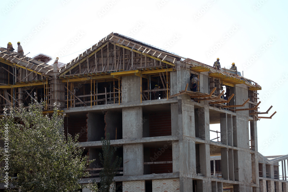 Construction workers build a multi-story residential building in a sunny environment during the day Construction workers build a multi-story residential building in a sunny environment during the day