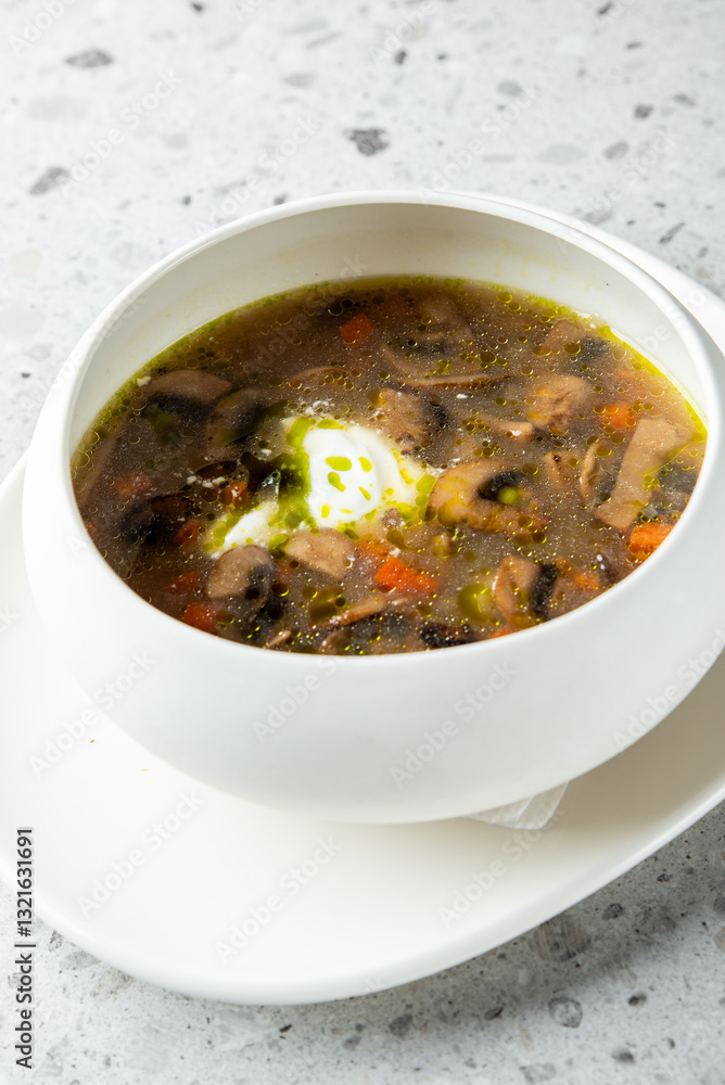 A delicious bowl of soup featuring vegetables, mushrooms, and a poached egg, served in a sleek white dish on a light textured surface. A delicious bowl of soup featuring vegetables, mushrooms, and a poached egg, served in a sleek white dish on a light textured surface.