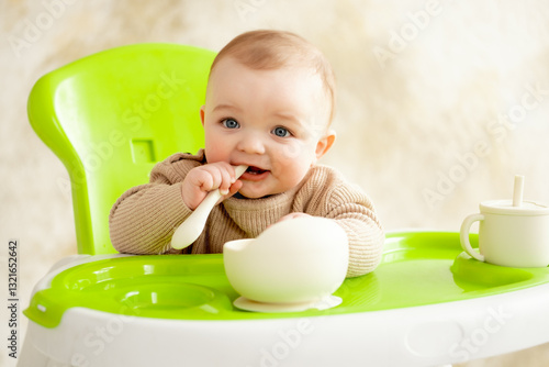 a baby in a green high chair eats, baby food concept, place and space for text photo