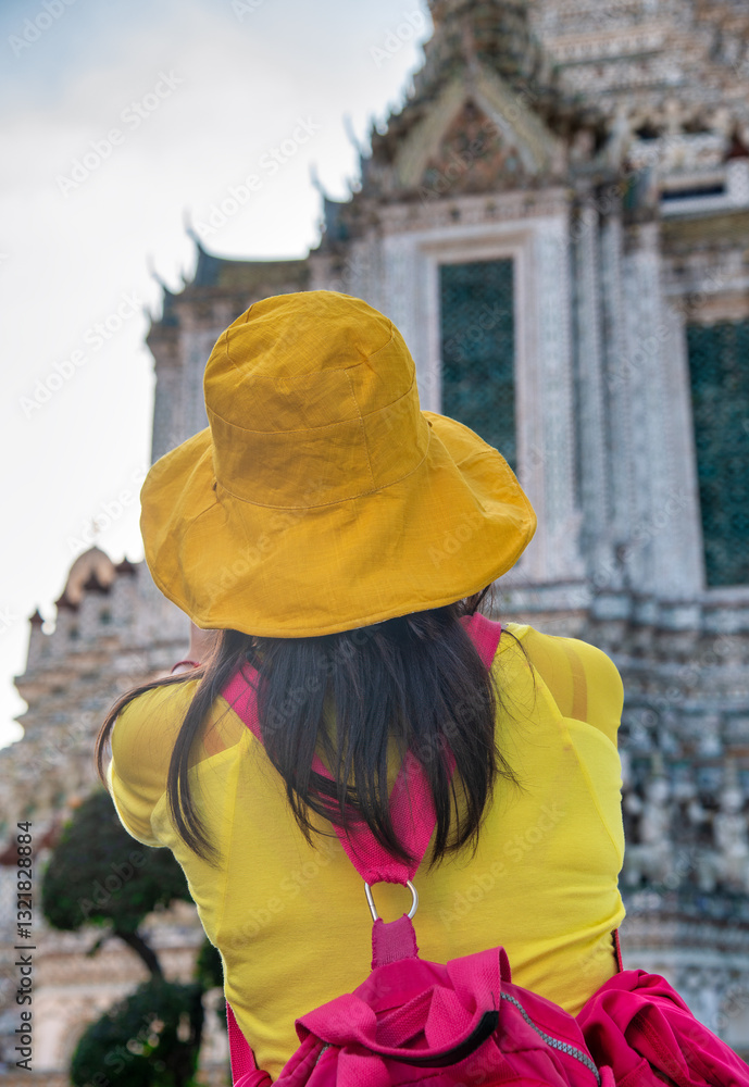 Tourist girl visiting Wat Arun, the Temple of Dawn, in Bangkok during daytime