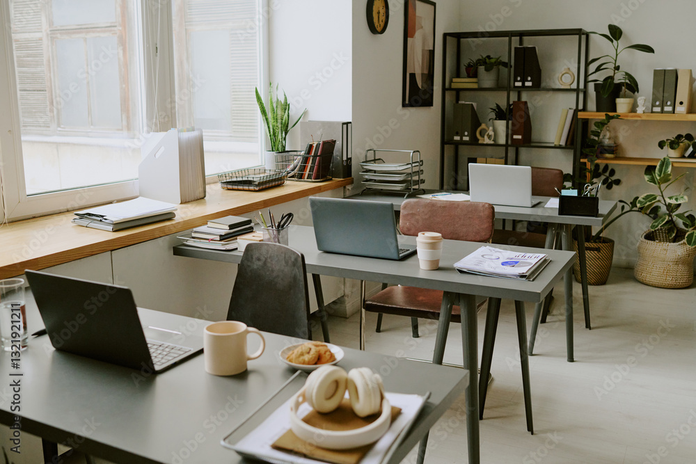 High angle shot of modern office with several workplaces with workers belongings and digital devices on desks High angle shot of modern office with several workplaces with workers belongings and digital devices on desks