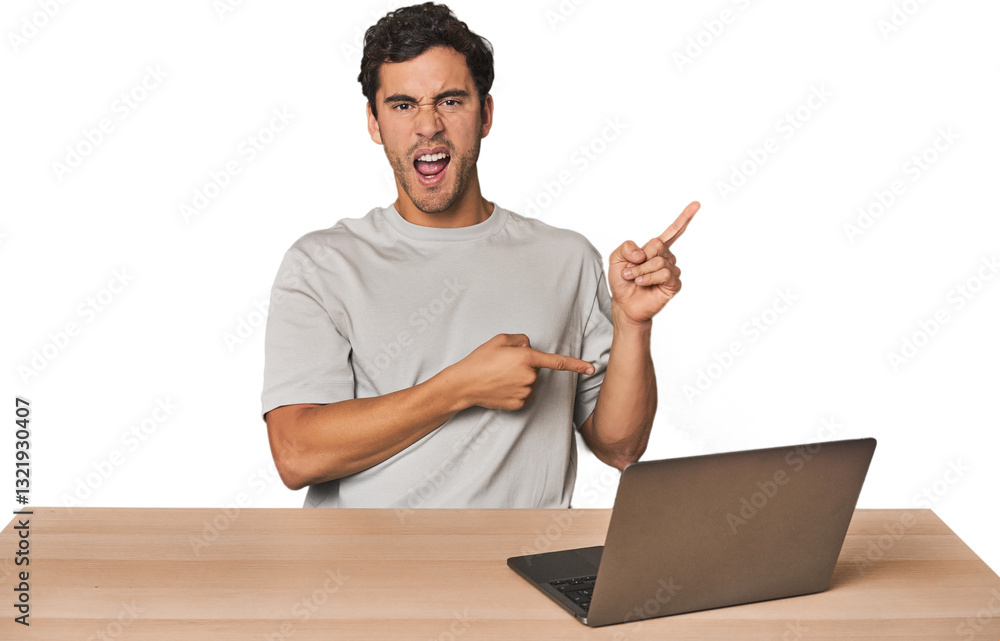 Hispanic young man working on laptop pointing with forefingers to a copy space, expressing excitement and desire. Hispanic young man working on laptop pointing with forefingers to a copy space, expressing excitement and desire.