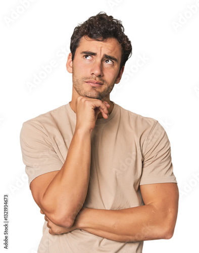 Canvas Print Young Hispanic man in studio thinking and looking up, being reflective, contemplating, having a fantasy