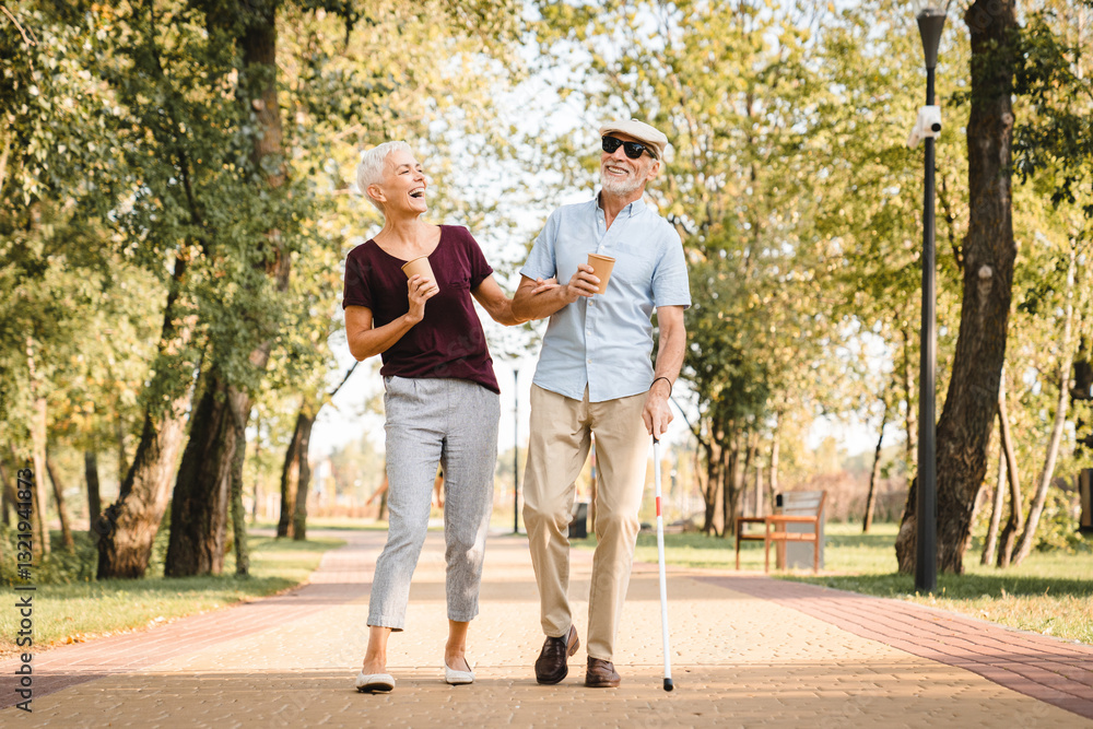 Elderly couple walking in the park. Senior man is blind and senior woman helping him to walk. Senior couple spending time in nature. Senior couple enjoying outdoors retirement. Elderly couple walking in the park. Senior man is blind and senior woman helping him to walk. Senior couple spending time in nature. Senior couple enjoying outdoors retirement.