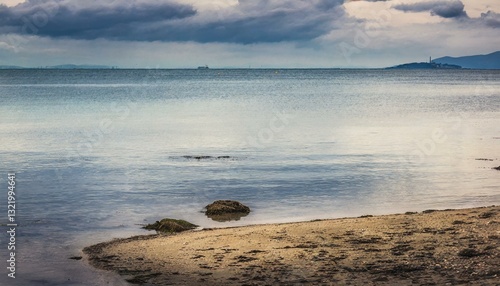 Gentle cliffs and a calm shoreline stretch beneath a hazy horizon, evoking a sense of tranquil coastal beauty.